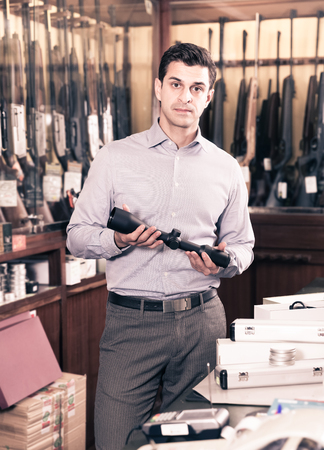 Positive male owner of hunting store offering ammunition and accessories for huntの写真素材