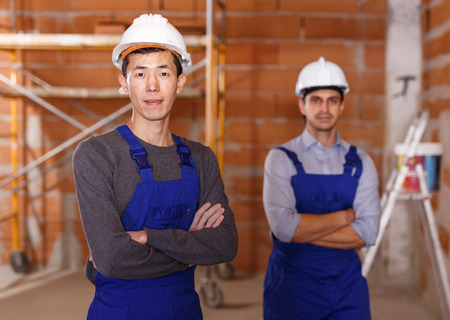 Portrait of two confident workers in uniform inside brick cottageの写真素材