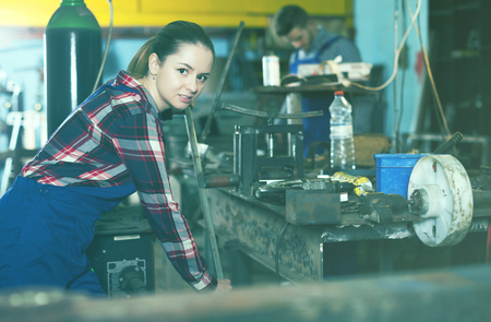 woman master is standing near vise equipment in workshop.の写真素材