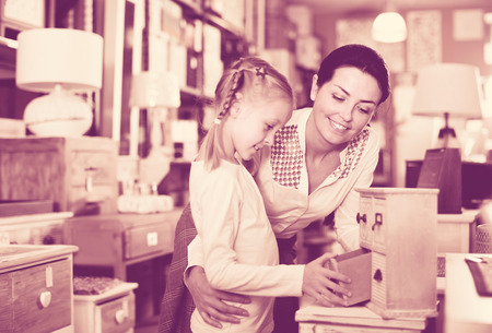 Smiling woman with daughter choosing new furniture for their home in the storeの写真素材