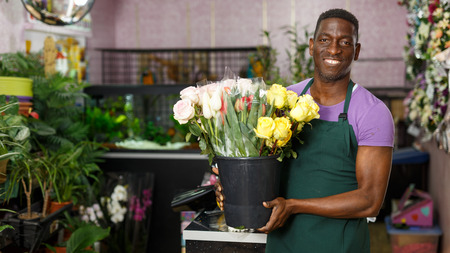 Portrait of successful African-American man owner of floral store standing with fresh flowersの写真素材
