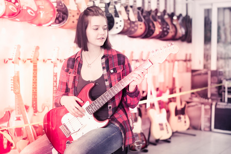 Teenage girl choosing best electric guitar in the guitar shopの写真素材