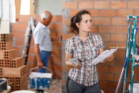 Thoughtful young woman working on her home renovations, looking at list of works

の写真素材