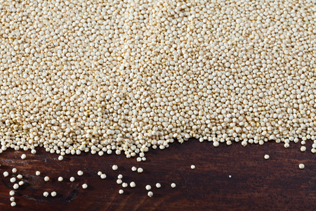 Closeup of raw seeds of white quinoa on dark wooden background. Healthy and nutritious foodの写真素材
