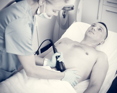 Female specialist is massaging with vacuum to belly of client for anti-fat in estetic clinic.