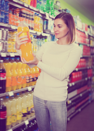Adult woman choosing refreshing beverages in supermarketの写真素材
