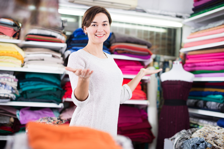 Female shop assistant demonstrating assortment at drapery shopの写真素材
