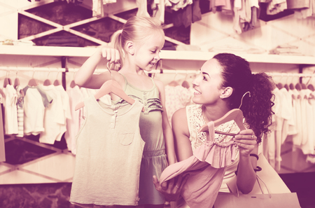 portrait of happy russian  woman and girl shopping kids apparel in clothes storeの写真素材