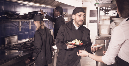 Kitchener is giving order to female waiter in restaurant.の写真素材