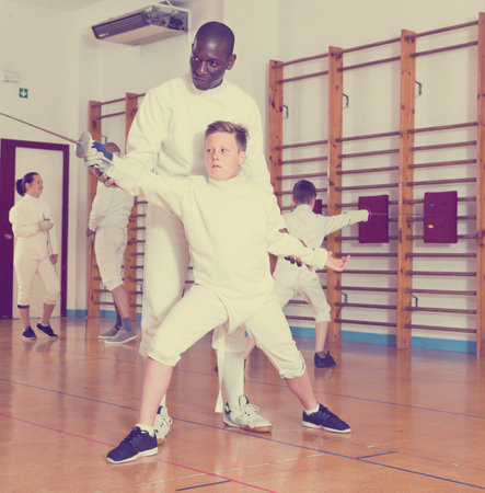 Fencing instructor explaining to young fencers an effective movements and techniques in a training...