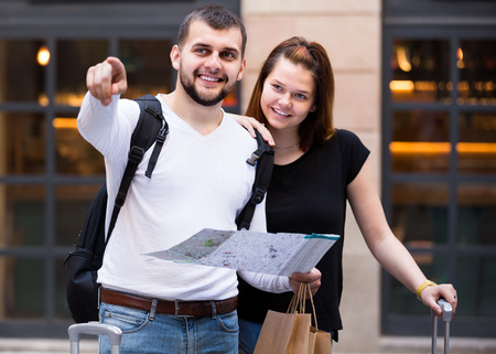 Happy man and woman traveling with map and baggage looking attractionの写真素材