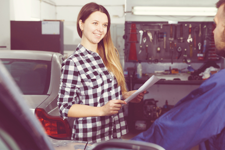 Smiling female is satisfied of tire replacement of her car in spring in workshop.の写真素材