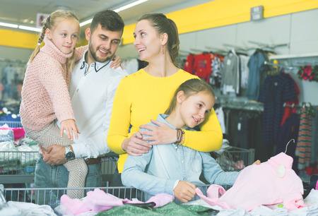 smiling young family with two little girls choosing new clothes in mallの写真素材