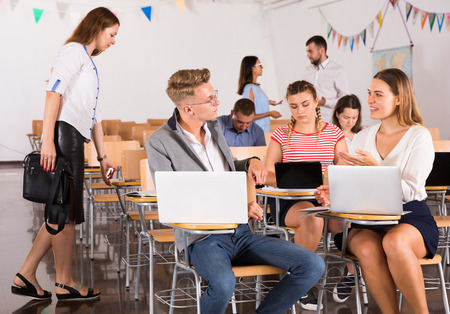 Smiling adult students communicating during recess between lectures in auditorium