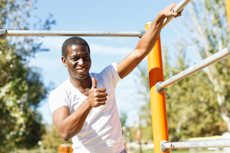 Portrait of active african  american man doing workout at pull-up bar  in parkの写真素材