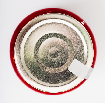 Top view of silver metal lid on glass jar with raspberry jam on white backgroundの写真素材