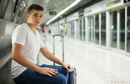 Portrait of young European man sitting in underground carriage and using his phoneの写真素材