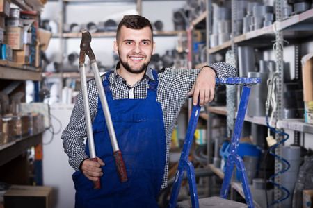 Smiling man worker showing various instruments at workplaceの写真素材