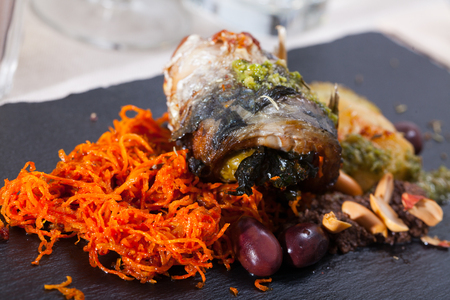 Delicious mackerel roll with bacon filling served with baked potato and grated carrotの写真素材