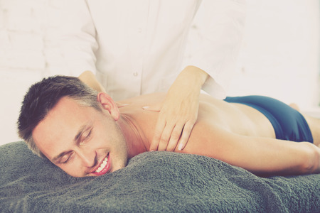 Woman massage therapist massaging positive brunette guyの写真素材