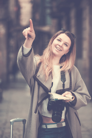 Positive girl having pamphlet and looking for her route in the cityの写真素材