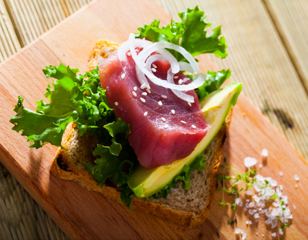 Image of  delicious sandwich with raw tuna,  avocado, onion and greens at plateの写真素材