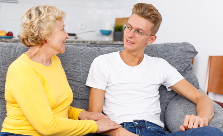 Happy young guy and his mother spending time together at homeの写真素材