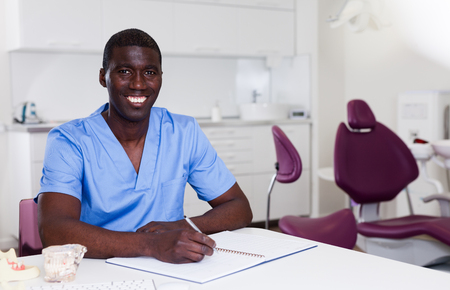 Confident male dentist working with medical records in dental officeの写真素材