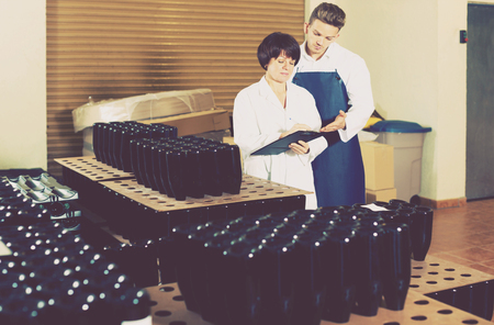 Happy employees checking number of wine bottles at sparkling wine factoryの写真素材