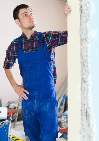 Puzzled builder handyman examining room and planning renovationの写真素材