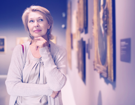 Positive adult woman near picture collection in the museumの写真素材