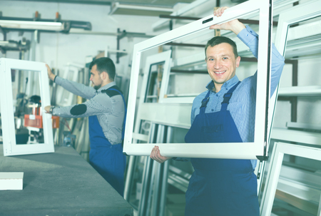 Young production workers in coverall with different PVC windows and doorsの写真素材