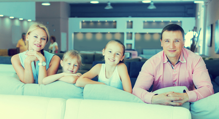 Parents with their children are choosing new sofa in furniture store.の写真素材