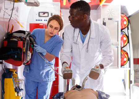 professional afro paramedical using defibrillator for providing medical care to patient outdoor