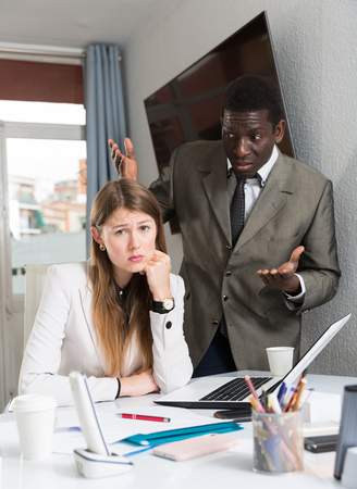 Unhappy man boss scolding mistakes in work  to young female manager in officeの写真素材