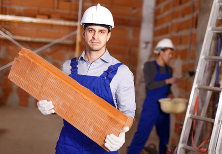 Portrait of two confident workers in uniform inside brick cottage