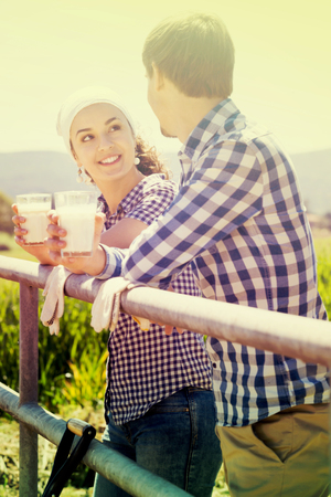 Portrait of smiling man and woman taking a pause and holding glass with milkの写真素材