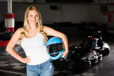 Portrait of young woman holding helmet at kart circuitの写真素材