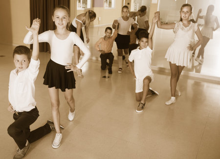 Smiling adult children  enjoying of partner dance in class