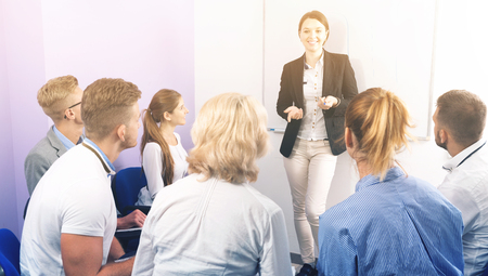 Glad  female speaker giving presentation for  students in lecture hallの写真素材