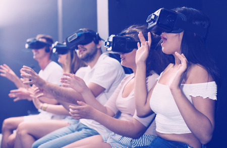 Excited woman is experiencing with friends virtual reality in entertainment room.の写真素材