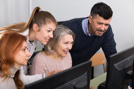 Young and mature business people grouped around computer monitor  in office