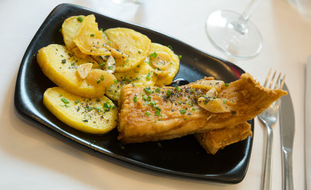 Basque Country cuisine. Fried skate wings a la Santurce with baked potatoes