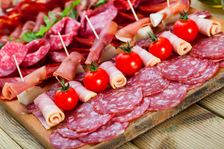 Spanish sausage cutting â fuet, jamon, chorizo, olives on wooden boardの写真素材