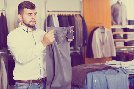 Portrait of businessman buying new pair of pants in men storeの写真素材