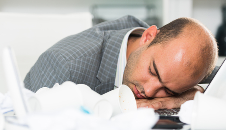 Young sad man tired of working and sleeping in the modern officeの写真素材