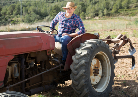 Positive man working on farm tractorの写真素材