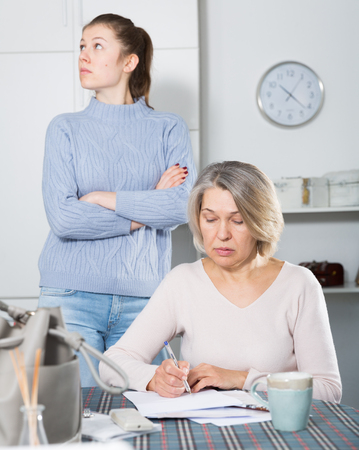Outraged adult daughter having disagreement with her mother for problems with filling documentsの写真素材