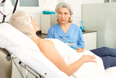 Doctor beautician polls a patient at the clinicの写真素材