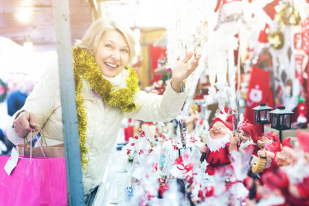 Woman is preparing for Christmas and choosing decorations for her house outdoor.の写真素材